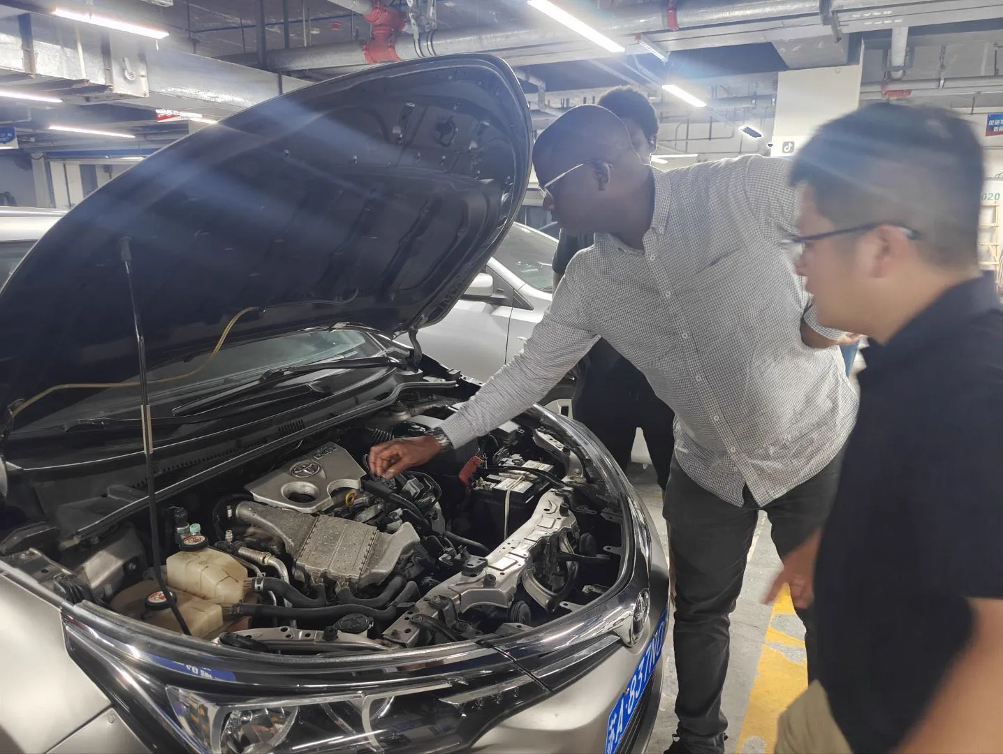 A client and the Xincheng Auto team inspecting a vehicle engine bay